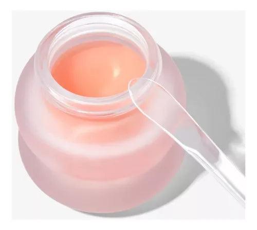 Tarro de crema facial rosa con textura gel y espátula transparente sobre fondo blanco