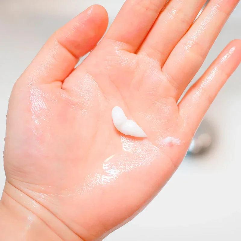 Mano con crema blanca hidratante y gel transparente en la palma, piel limpia y suave
