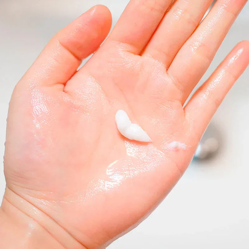 Mano con crema blanca hidratante y gel transparente en la palma, piel limpia y suave
