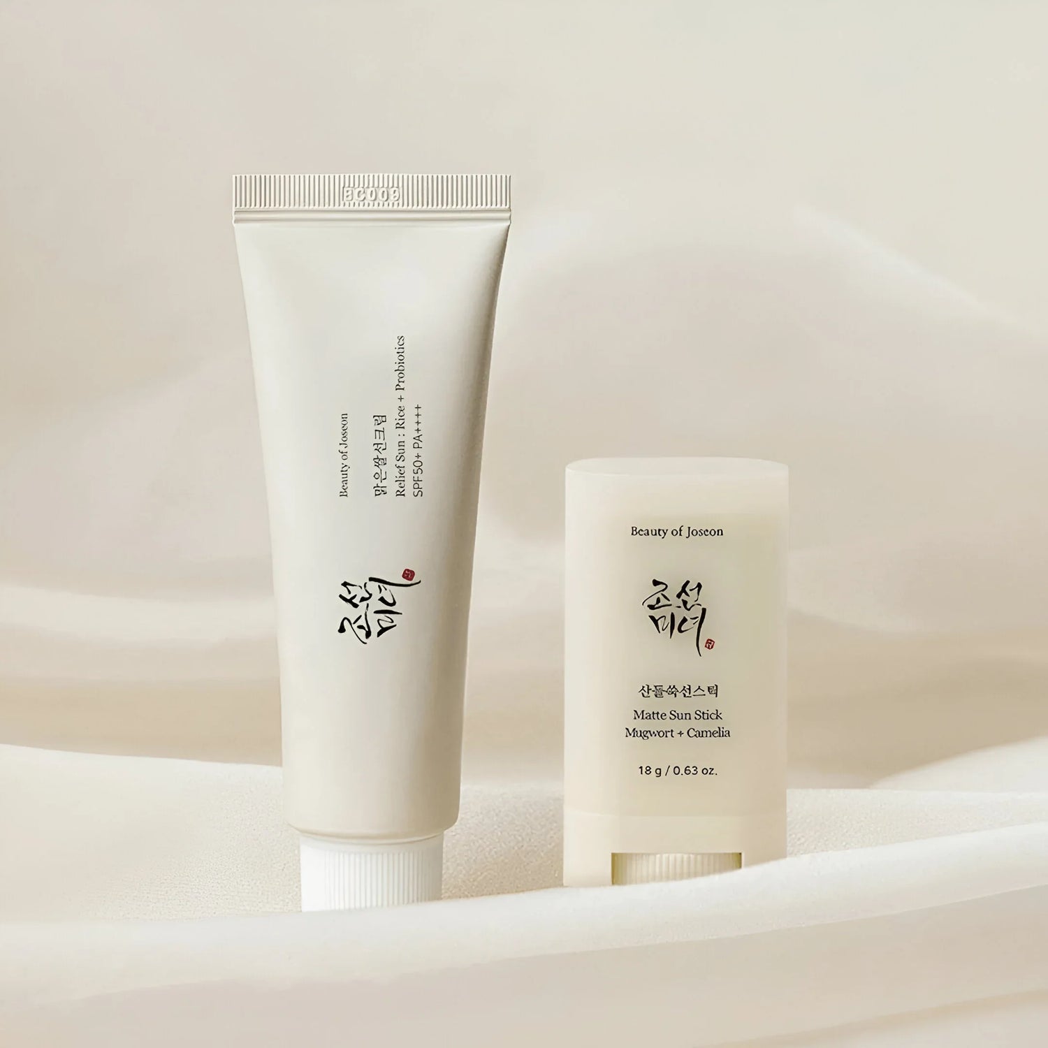 Protector solar Beauty of Joseon, crema en tubo y stick solar mate sobre tela beige